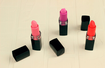 Three female lipsticks of red, purple and pink colors. Women's cosmetics for makeup.