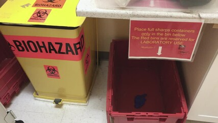 Biohazard medical waste disposal room at hospital clinic, tilt down.