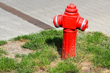small red with white and gray fire hydrant on the background of the road and grass in the summer in the city