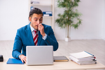 Sick male employee suffering at workplace from coronavirus