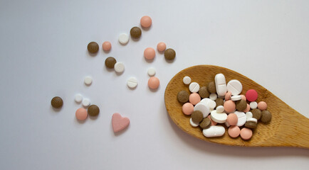 Mixed medicine pills, tablets on wooden spoon on white background with space for text. Different pills and tablets. Pharmaceutical pills and tablets. Flat lay of medicine pills and tablets