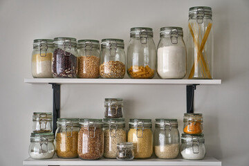 Glass jars with a lid for food. Storage of cereals, pasta, peas, rice in the kitchen. Containers with bulk products. Jar on the shelf. KORKEN-transparent glass.