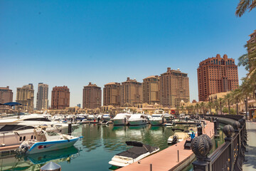 Doha, year 2019: Private yachts and boats in The Pearl of Qatar marina. Expensive buildings, shops and a million dollar lifestyle in the Middle East.