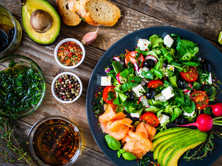 Breakfast - smoked salmon, feta cheese, avocado and vegetable salad on wooden table 