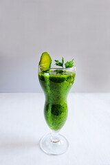 Cucumber green homemade cocktail in a tall glass glass stands on a light table. Ingredients-cucumber, spinach, parsley. The concept of healthy eating, detox