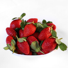 Ripe strawberries in a white plate on a white background