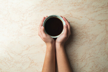 a top view of a hands holding a cup of coffee