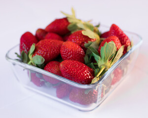 Ripe strawberries in a glass plate on a white background