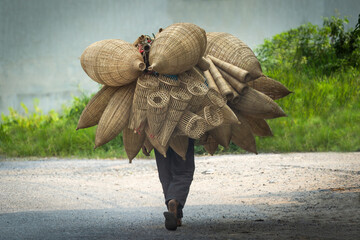 Old men are walking for selling wicker craftsman making traditional bamboo fish trap or weave in Hanoi, Vietnam