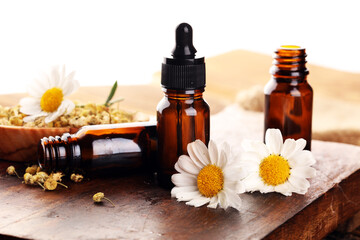 Chamomile Composition with essential oil and chamomile flowers on wooden rustic table