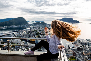 Trip to Norway. Young woman with brown hair enjoy panoramic view of Alesund city on sea and islands...