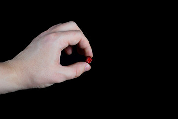 fingers holding one dried cherry berry on a black background