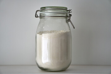  Glass jars with a lid for food on a white shelf. Storage in the kitchen. Containers with bulk products. Transparent container.