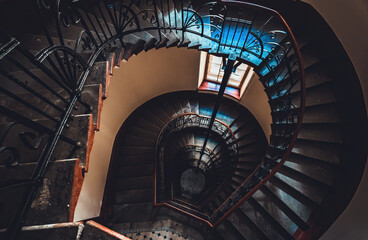 Destroyed spiral staircase indoors. Natural light. Beautiful architecture. Old apartment building in Saint Petersburg. Winding stair. Devastated ruins