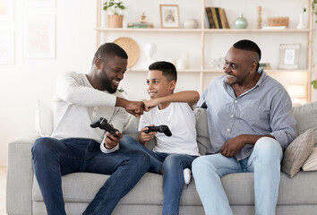 Happy senior man watching his son and grandson playing video games