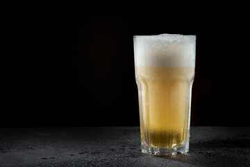 A glass of light beer on a dark background
