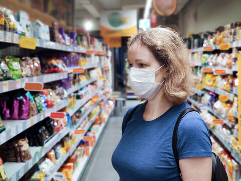 Coronavirus And Retail Concept, Young Woman Wearing Medical Mask Looks At Grocery In Supermarket. Consumer In Disposable Face Mask Shopping Food