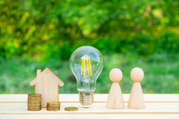 Family concept. Wooden house, family and lightbulb on a wooden table. Utility bills. Family budget....