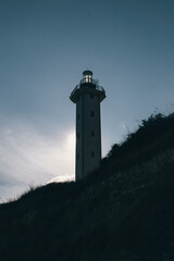 bottom view of a lighthouse on a coast hiding the sun