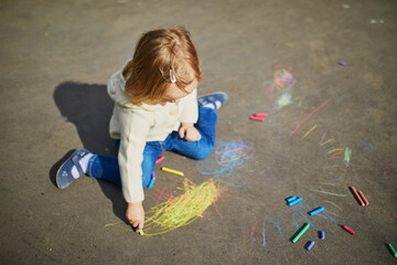 Naklejka premium Adorable toddler girl drawing with colorful chalks