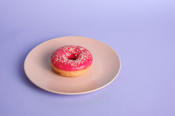 Pink red donut with white sprinkles on pink plate, sweet glazed dessert food on blue minimal background, angle view