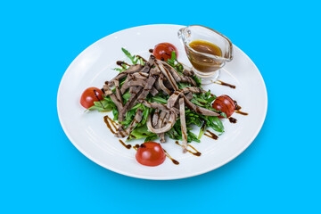 Arugula salad with beef tongue and honey-mustard sauce isolated on blue