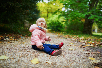 Adorable cheerful toddler girl in autumn park in Paris