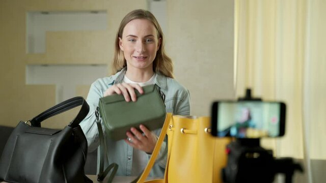 A female blogger shows fashion bags live on social media recording her sale online using a digital camera