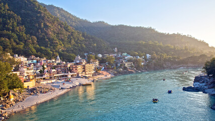 Fototapeta premium Rishikesh, Uttarakhand/India - November 17, 2013: People enjoying river rafting at river Ganga (Ganges) during sunset. The holy place is surrounding by Ashrams and the Himalayas.