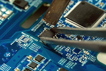 Electronics engineer repairs a chip in the workshop. Repairman heats the chipset using soldering...