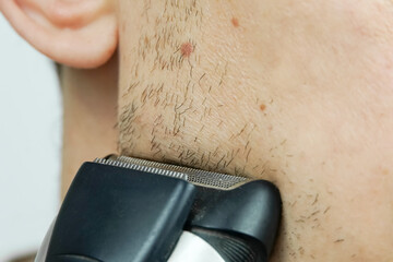 Man shaves with an electric razor close up