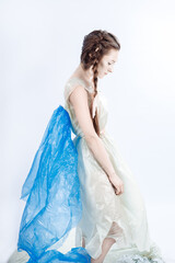 A trash angel. the girl in the trash bag clothes bowed her head sadly. Blue garbage bags hang over...