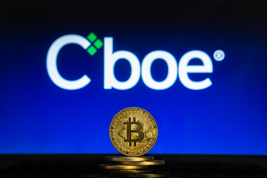 Bitcoin on a stack of coins with Cboe logo on a laptop screen. Cryptocurrency and blockchain adoption. Slovenia - 02 24 2019