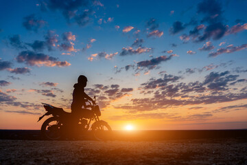Fototapeta premium Biker sitting on his bike&nbsp;against the sunset. While traveling on bike.&nbsp;