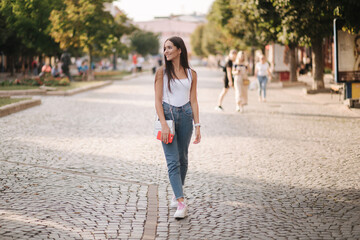 Attractive young woman walking by herself in centre of city in summer time. Woman walk alone. Happy...