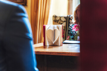 Open book standing on table. Book pages folded to heart shape. Symbol of love.