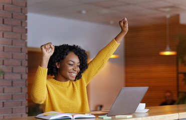 Emotional woman looking at laptop and screaming, working at cafe