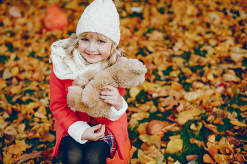 Cute child in a autumn park. Elegant little lady with blonde hair