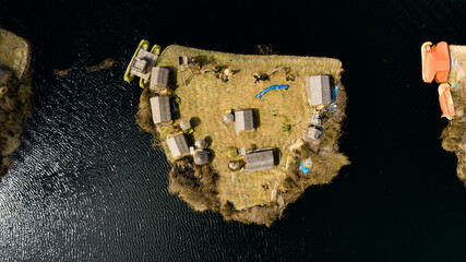 Aerial top view photo of one isolated floating island on Lake Titicaca in Peru without the tourists or people, visible houses, and a boat made of Totora plant.