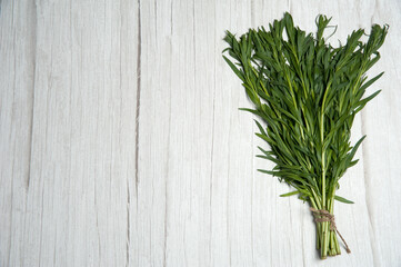 A bunch of fresh green tarragon close-up on a wooden background. An ingredient for soup and salad. Free space.