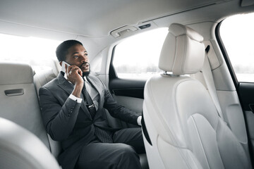 Businessman Talking On Phone Sitting On Back Seat In Car