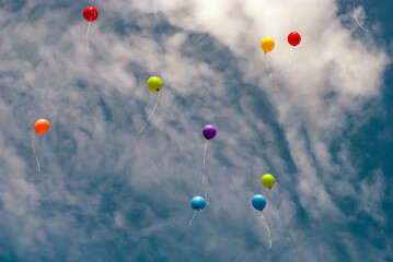 Several Colourful Baloons Flying Away on the Spring Blue Sky with the Clouds Background - Closer