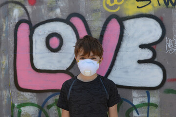 Little Boy with Mask on standing in front of graffiti spelling out 