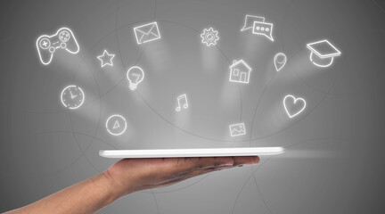 Hand holding tablet with hologram of online services icons