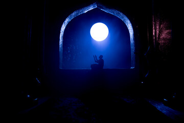 A realistic Arabian interior miniature with window and columns. Silhouette of muslim praying on carpet near window. Festive greeting card, invitation for Muslim holy month Ramadan Kareem.