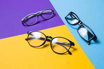 several pairs of glasses lie on a colored background, glasses for adults and children, top view, copy space, focus in the foreground