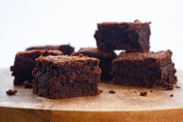 Homemade chocolate brownies on wooden board isolated on white background, close up side view, selective focus