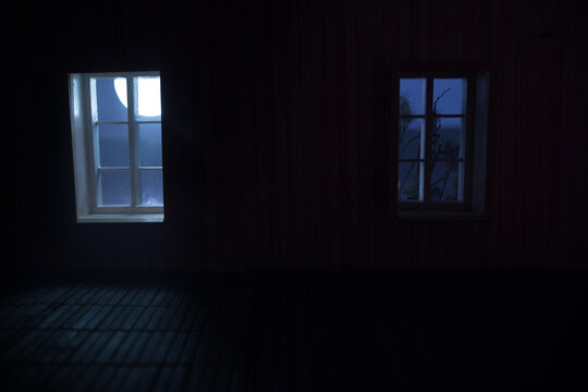 Night scene of moon seen through the window from dark room. Moonlight inside dark room