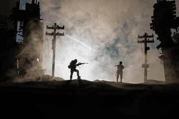 Fototapeta na wymiar Army sniper with large caliber rifle standing in the fire and smoke. War Concept. Battle scene on war fog sky background, Fighting silhouettes Below Cloudy Skyline at night. City destroyed by war