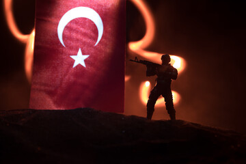 Silhouette of soldier with rifle against a turkish flag. Selective focus